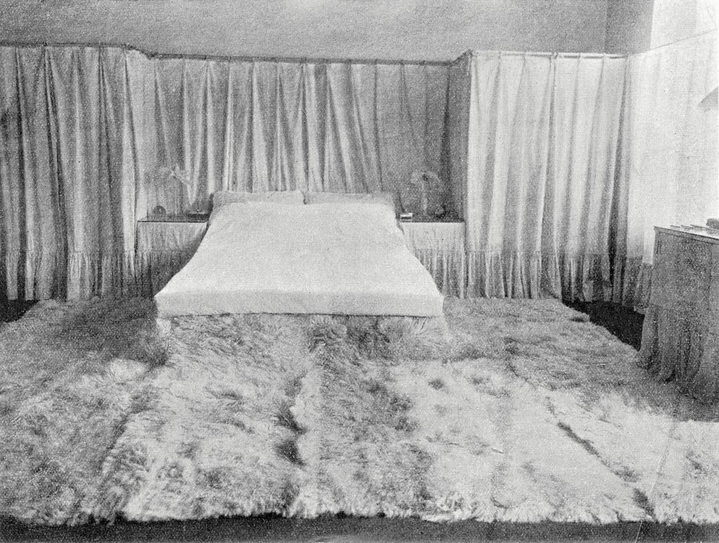 Doppelbett mit Vorhang dahinter und Fellteppich