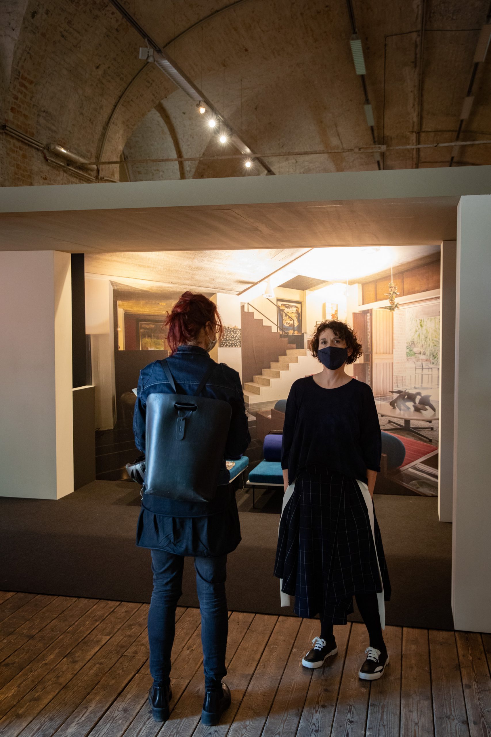 2 women in front of picture with a staircase