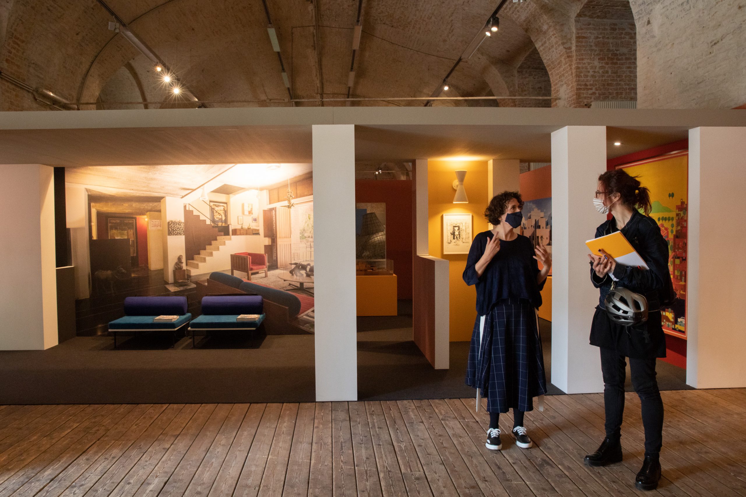 2 women stand in an exhibition room with mouth-nose protection