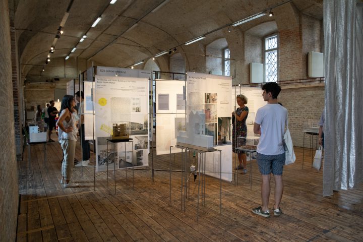 some people in exhibition room with white boards