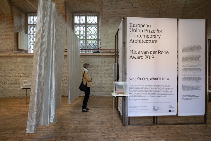 elderly woman with mouth protection standing in front of a plastic curtain
