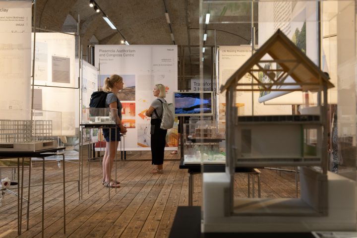 2 blond women with backpacks in exhibition with many models