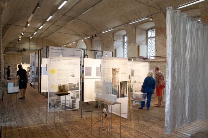 several persons in an exhibition room with brick vault