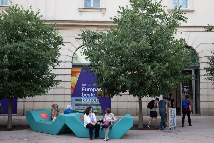 persons on turquoise seat parts, in the background 2 trees