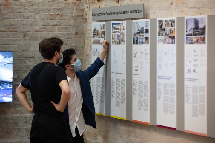 2 young men with face masks in front of exhibition boards