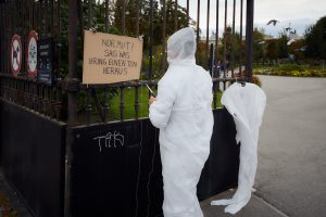 A person in a white full body suit in front of the park gate