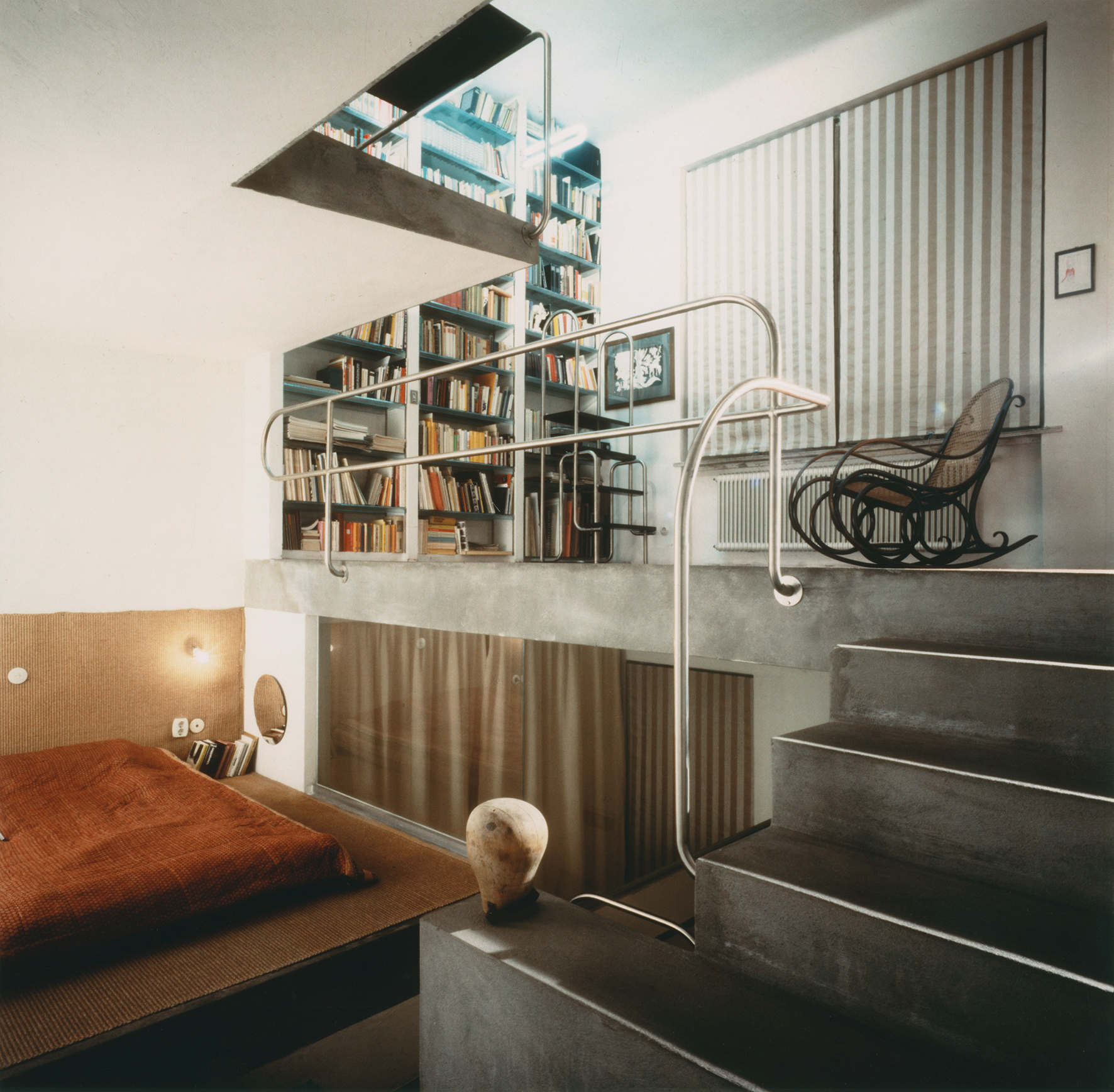 Room with steps, rocking chair, bed and high bookshelf