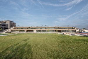 trapezoidal building in front of a large meadow