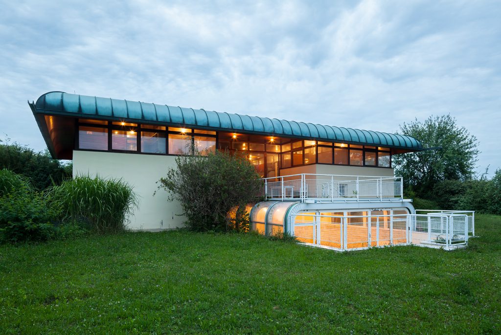 modern house illuminated inside with green meadow