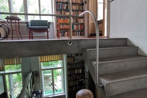 Residential house with open staircase, large bookshelf and many windows