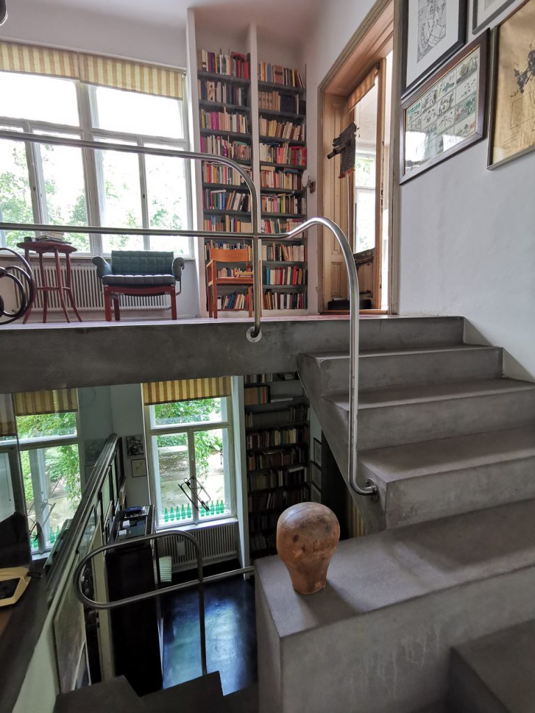 Residential house with open staircase, large bookshelf and many windows