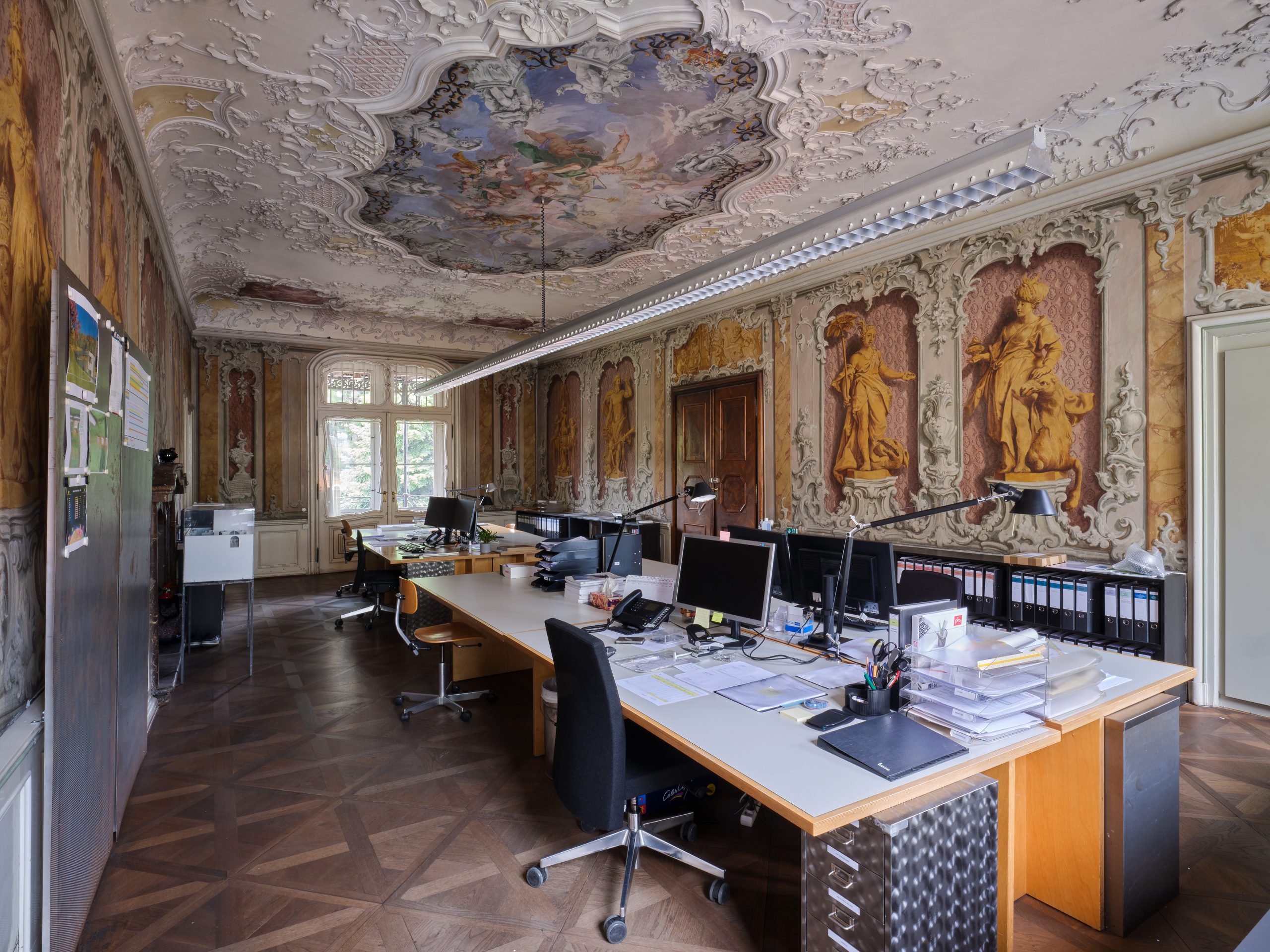 Large office desk in a room with stucco ceilings and frescoes