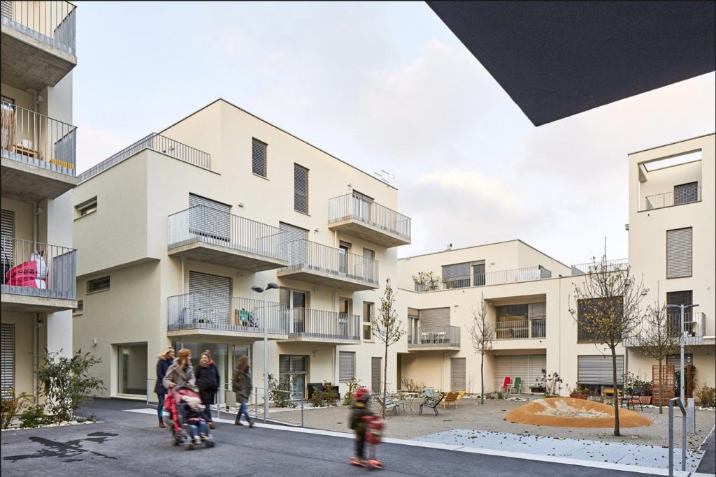 Wohnhäuser in beige mit Balkonen und kleinem Innenhof-Spielplatz