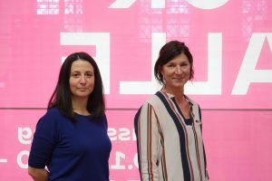 Two women against a pink background