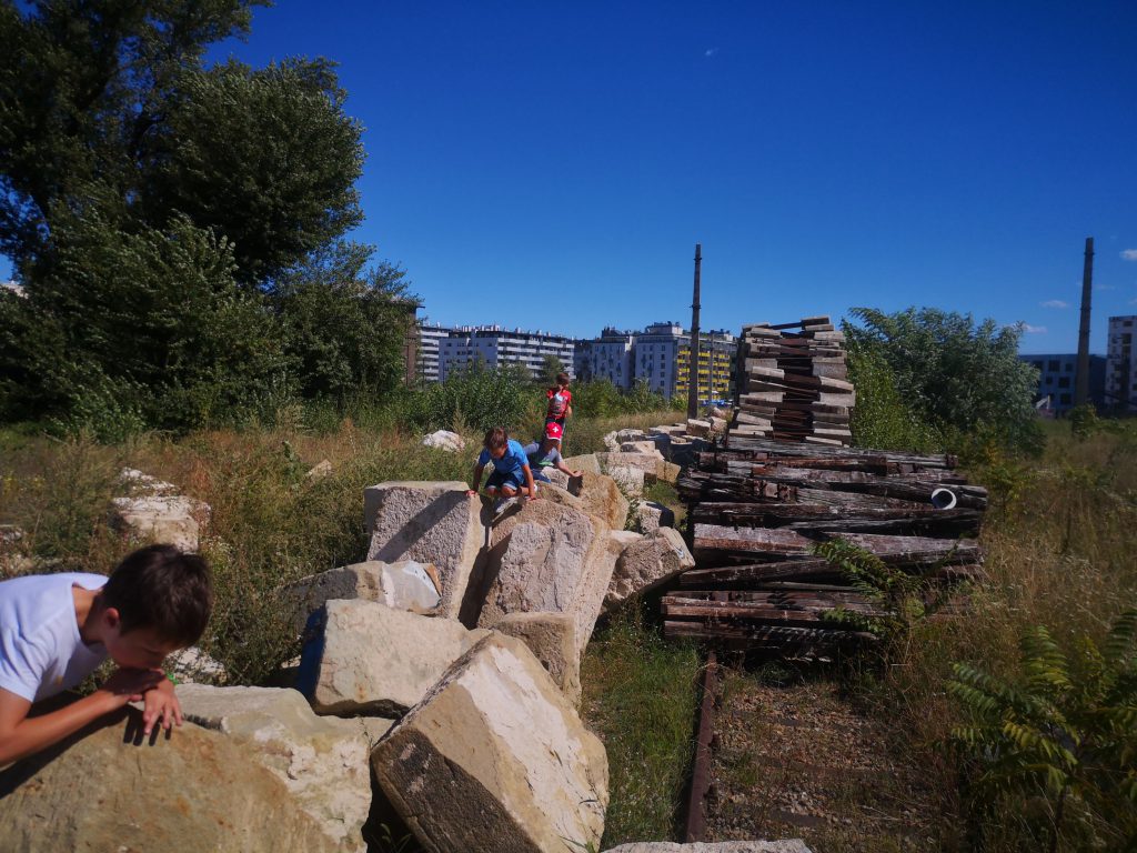 Children on large stones in a wasteland next to residential buildings