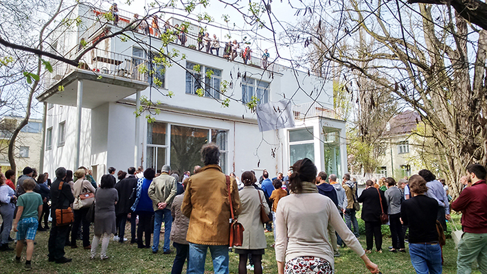 many people in a garden in front of and in a white house