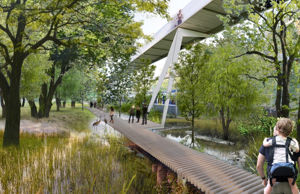 Fußgängerbrücke über eine Teich die durch einen Wald führt, im Vordergrund ein Mann mit Kind am Rücken