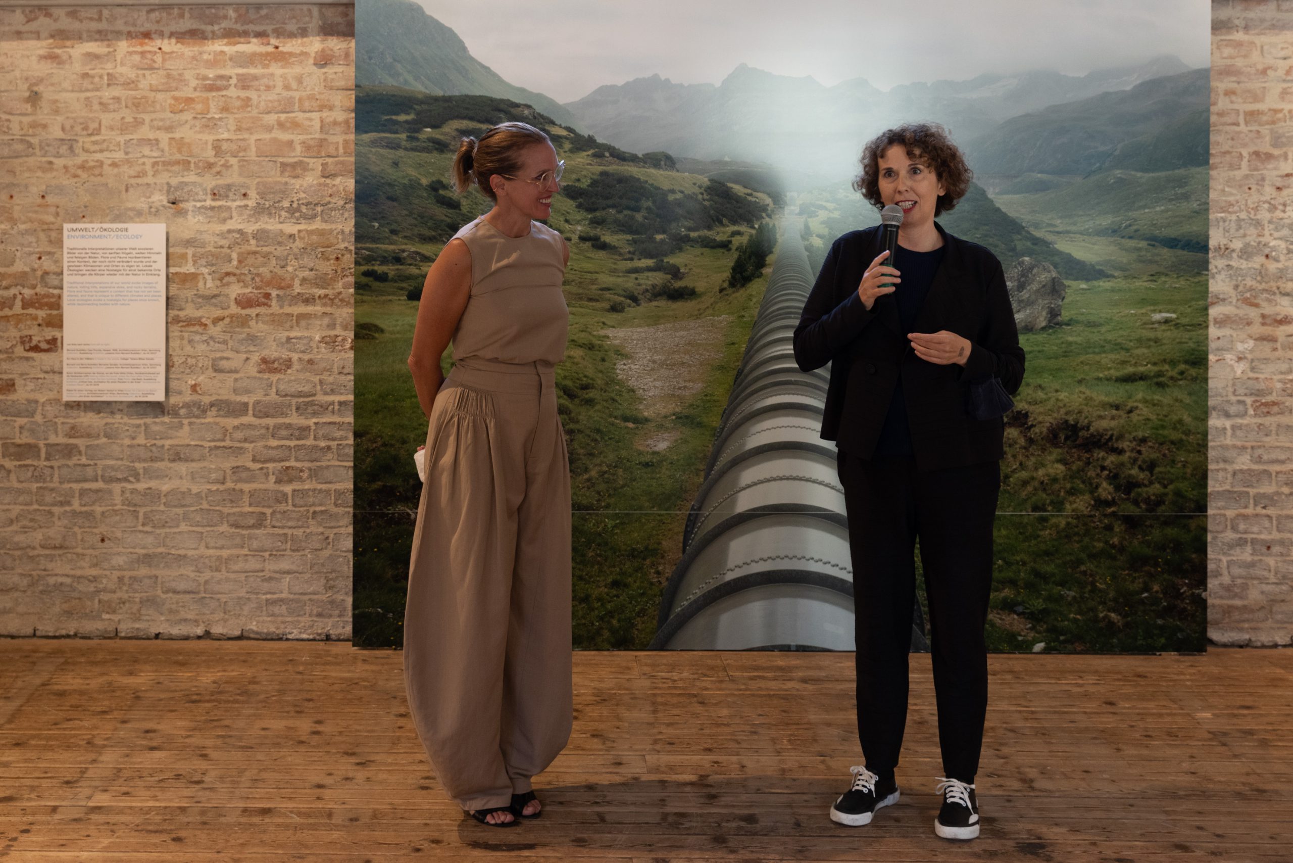 2 women in front of a very large photo with mountains