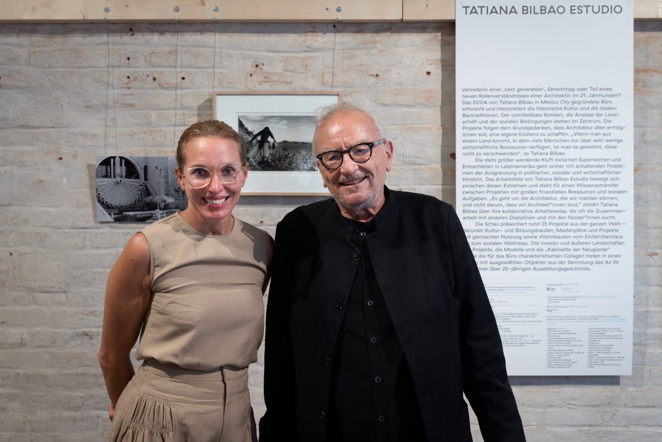 a woman with glasses and a man dressed in black with glasses