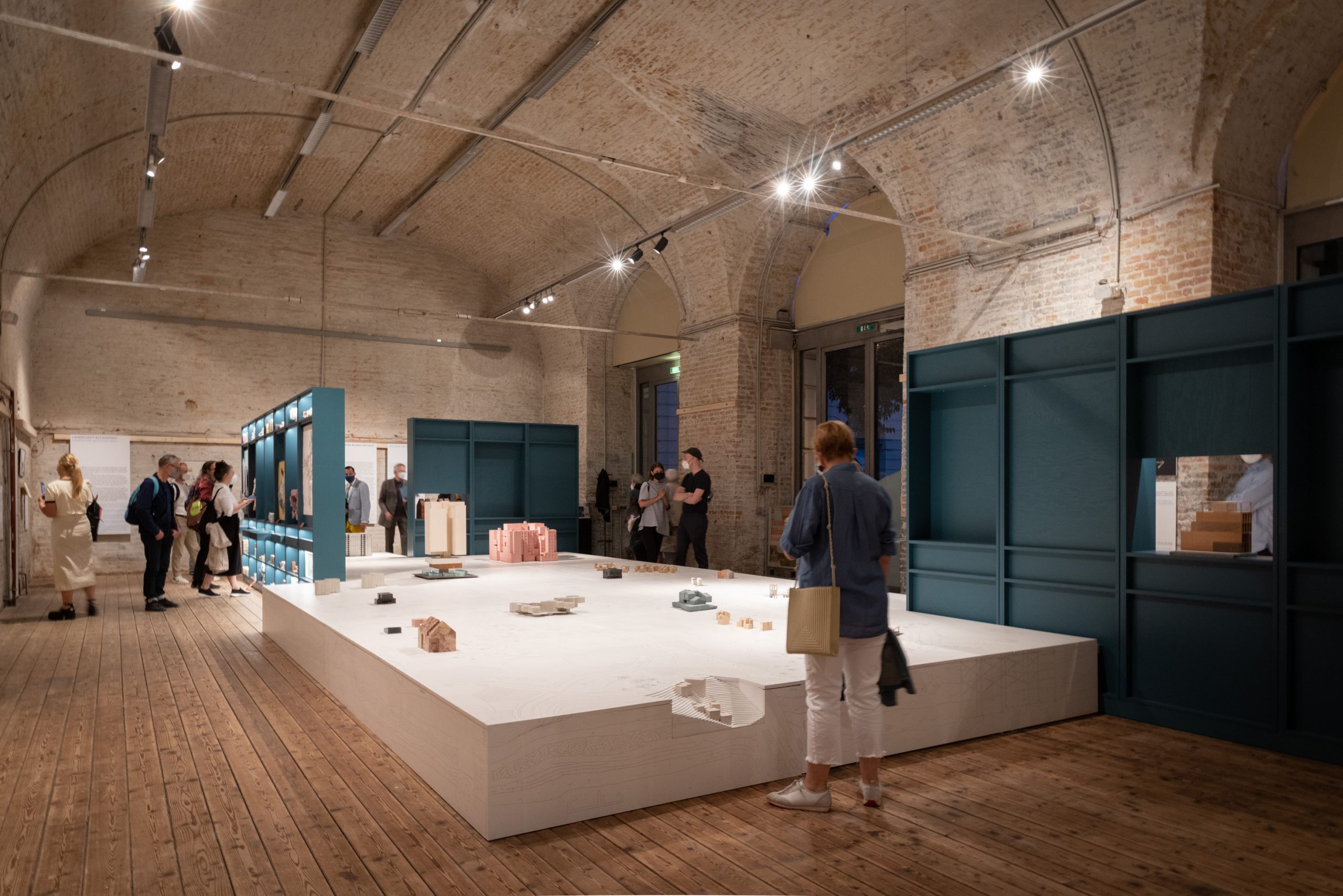 People in an exhibition room with petrol-coloured shelves