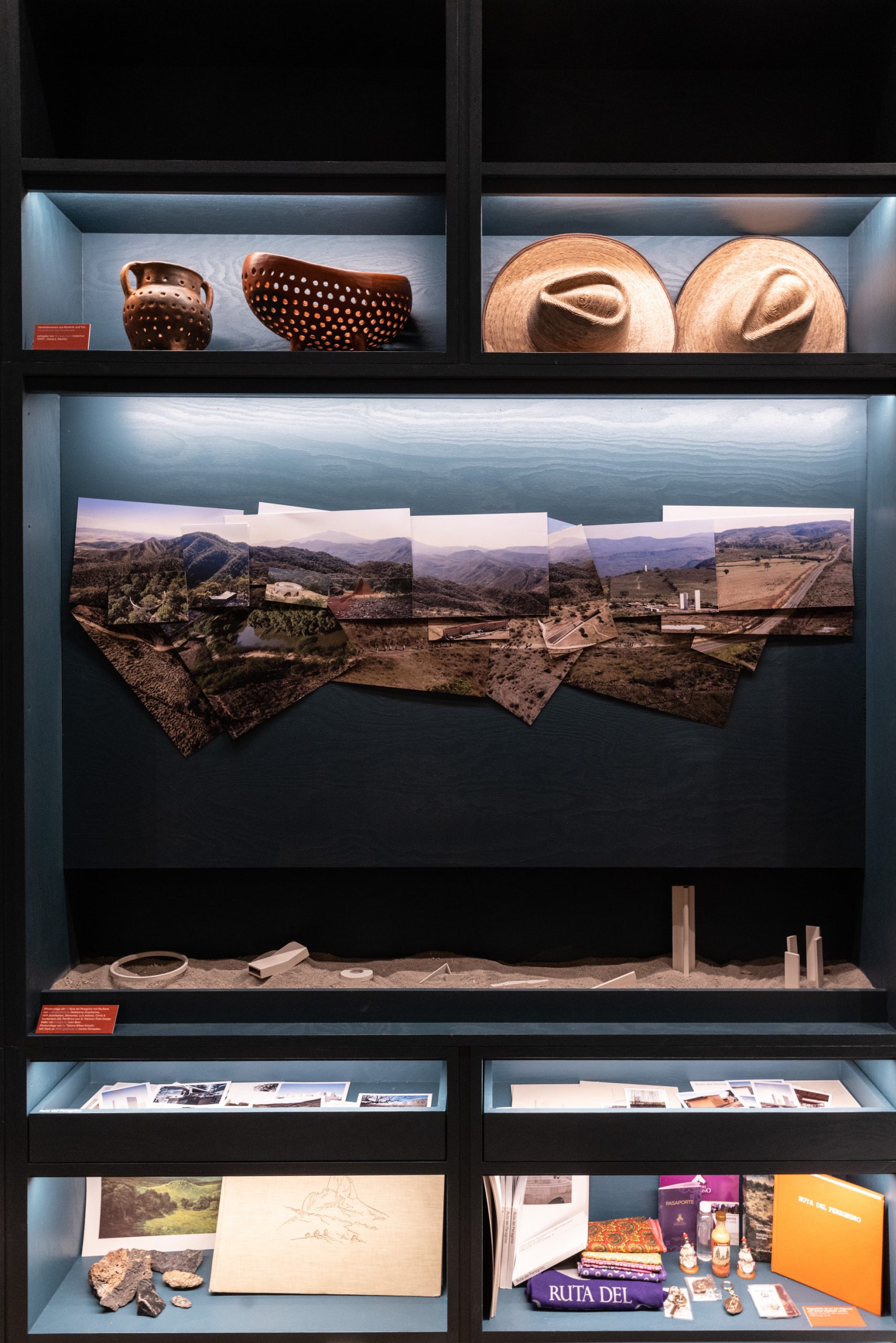 Objects on a dark shelf with hats, photos, stones