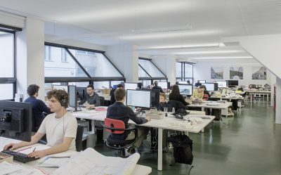 Office space with large slanted windows and many employees