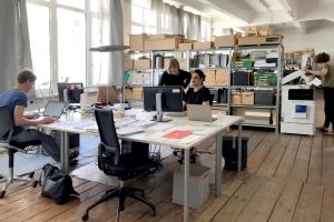 Office space with 4 people and shelf with many boxes