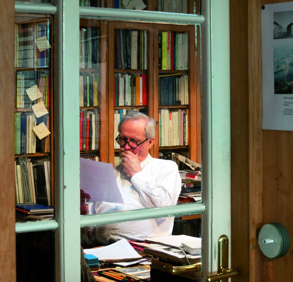 Hermann Czech sitzt auf seinem Sessel und liest ein Blatt