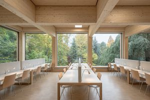 lange helle Holztische in großem Raum aus Holz mit großen Fenstern