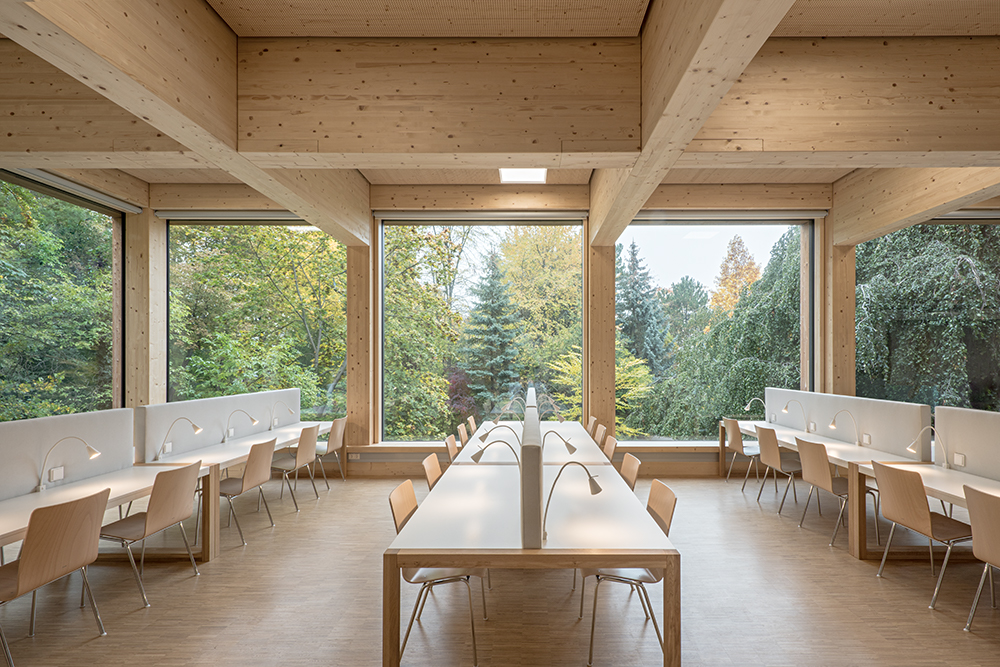 lange helle Holztische in großem Raum aus Holz mit großen Fenstern