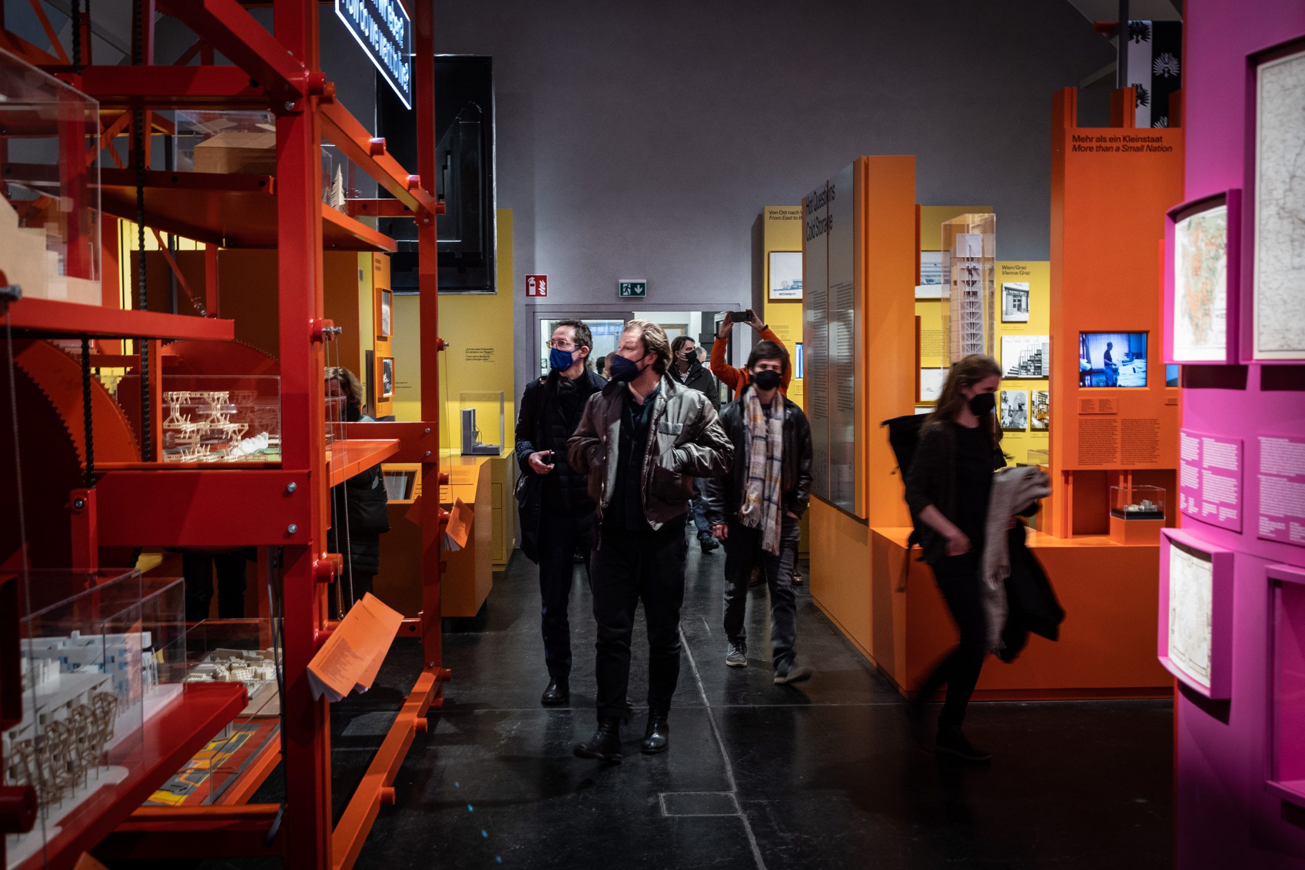 Gruppe von Menschen geht in Ausstellungsraum mit großen gelben, orangen und roten Ausstellungsinstallationen