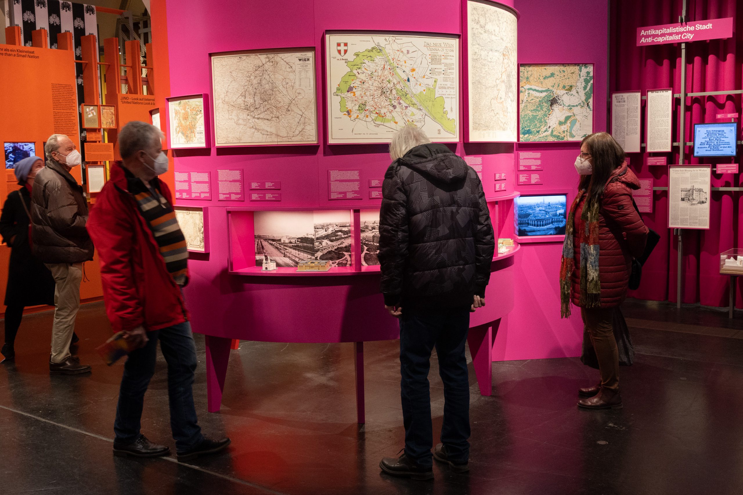 mehrere Personen in Ausstellung mit rosa und orangen Ausstellungswänden