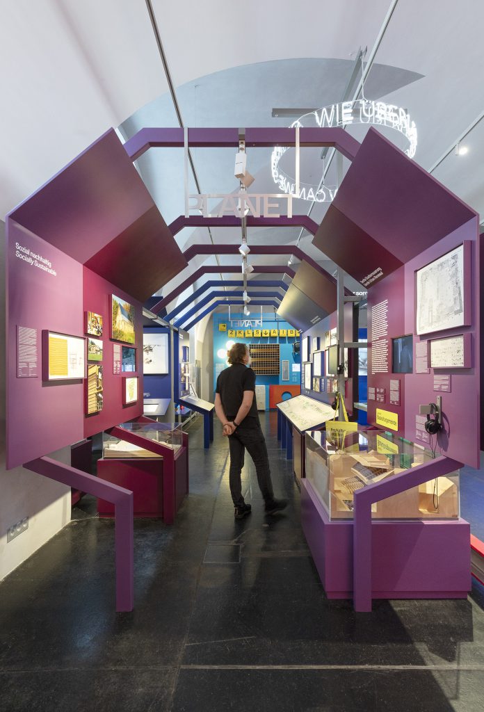 Mann in Ausstellung mit violetten Ausstellungswänden und -schaukästen