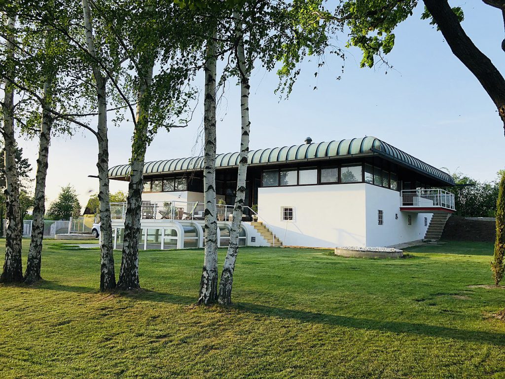 White house with rounded roof and six birch trees in front of it