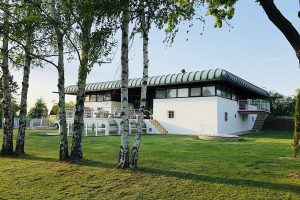 White house with rounded roof and six birch trees in front of it