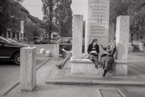 Zwei Frauen sitzen auf einem Denkmal