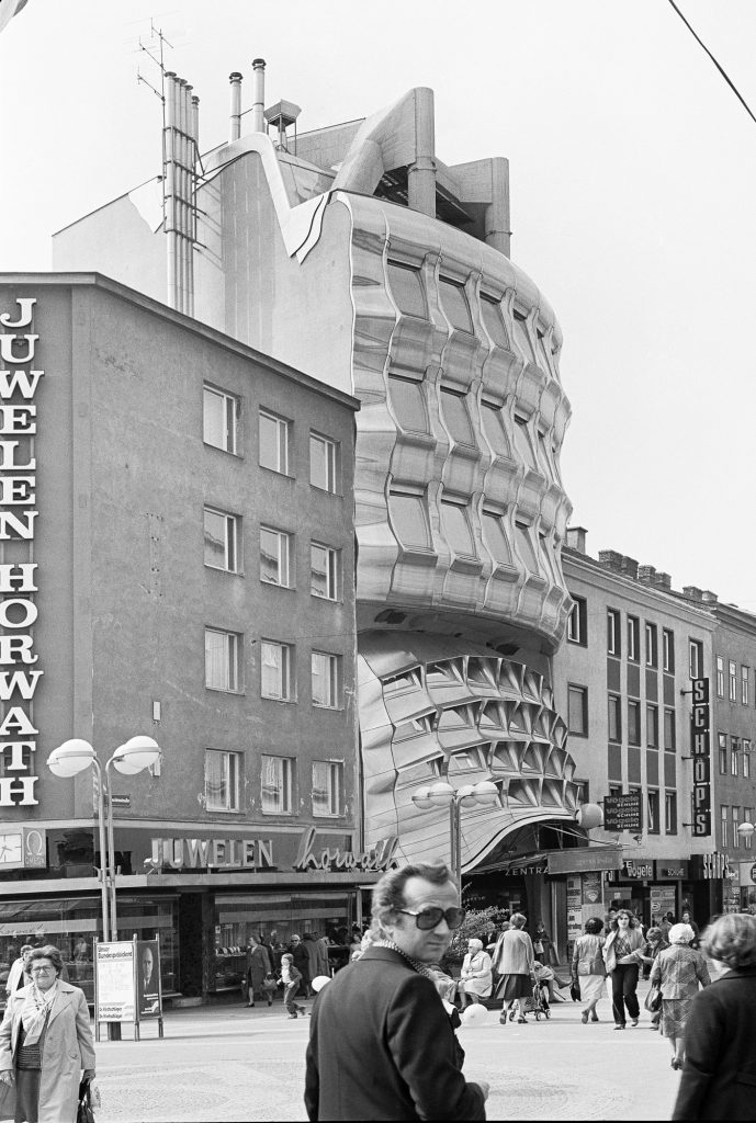 schwarz weiß Foto mit Häuserfront und Mann mit großer Brille davor