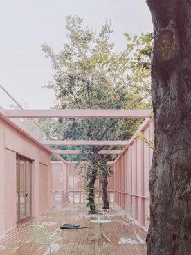Inner courtyard that is open to the top, 2 trees grow out in the middle and the building is antique pink