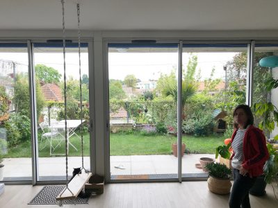 Woman standing in a room with a swing with large windows and garden behind it