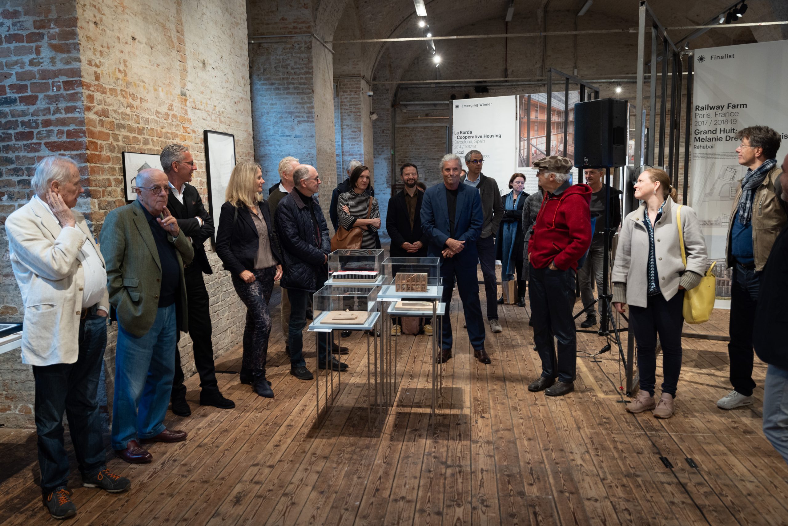 many people in a room in front of a small group of architectural models