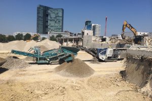 Construction site with several excavators and high-rise building in the background