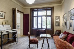 Room in old building flat with couch, armchair, large window and double door