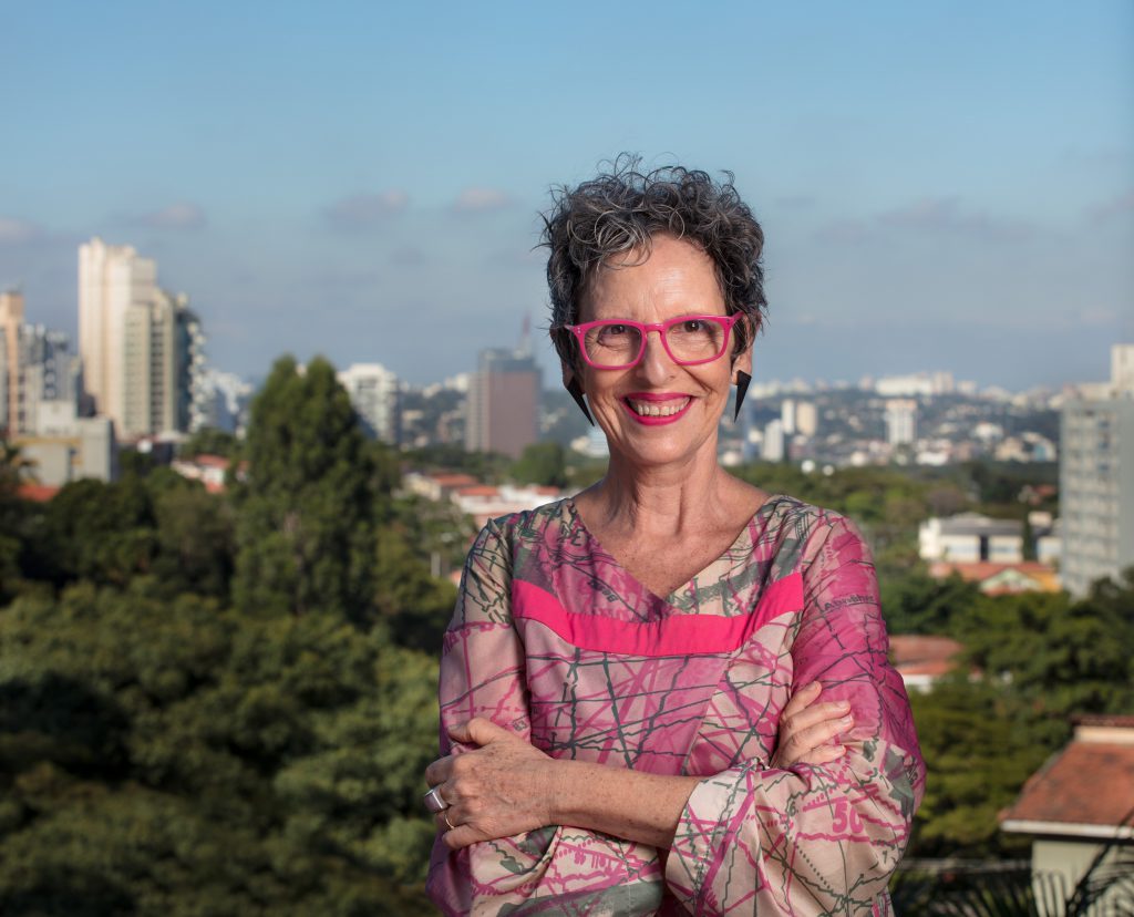 Laughing woman with pink glasses and pink-grey coloured blouse