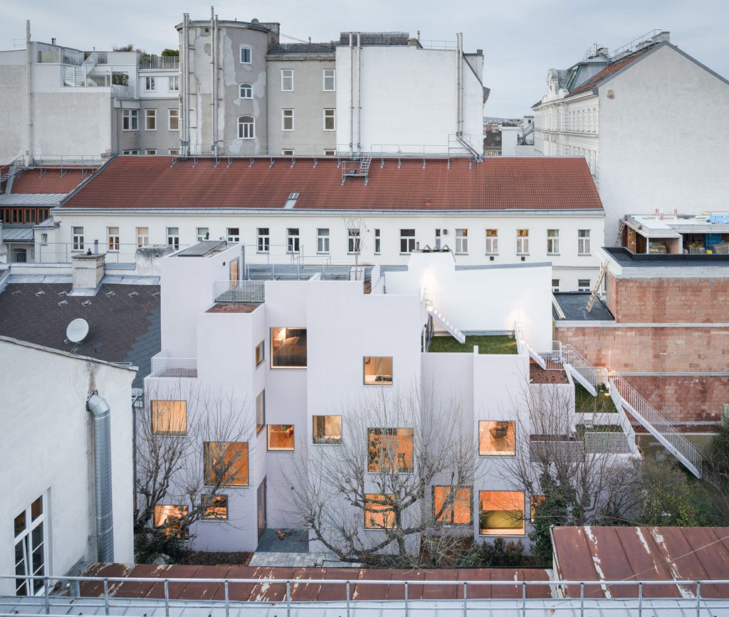 Courtyard in a city with a white house in the courtyard, large illuminated windows