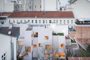 Innenhof in einer Stadt mit einem weißen Haus im Innenhof, großen erleuchteten Fenstern