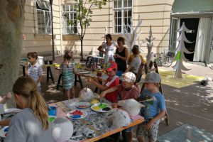 eine Gruppe von Kindern bastelt im freien auf Tischen