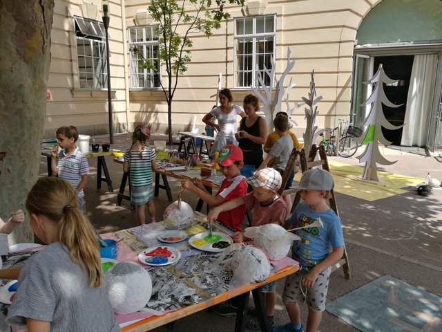 eine Gruppe von Kindern bastelt im freien auf Tischen