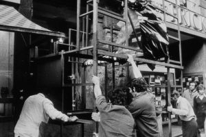a couple of men in a black and white photo trying to push a scaffold