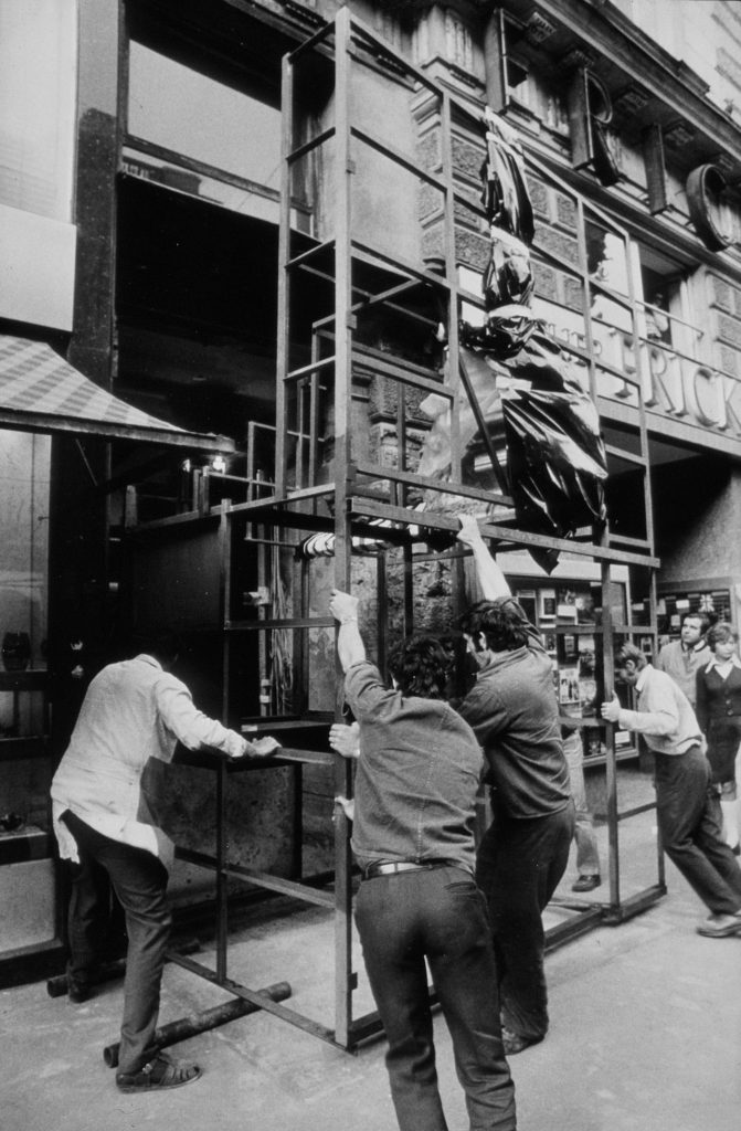 a couple of men in a black and white photo trying to push a scaffold