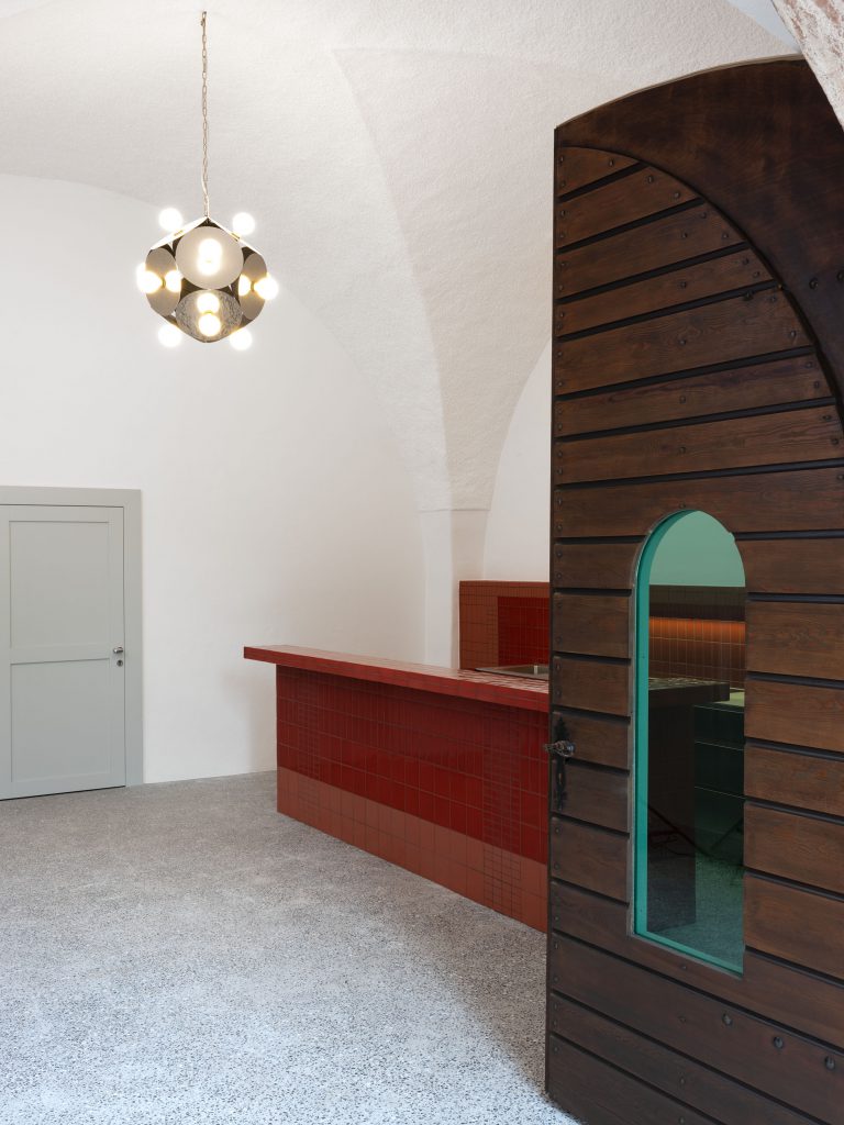 Raum mit Leuchte, Holztür und roter Bar
